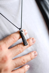 Men's silver engraved bar necklace worn close up around neck