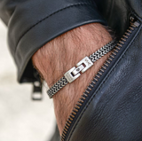 Close up of men's foxtail chain bracelet on wrist with zipper leather jacket stainless steel