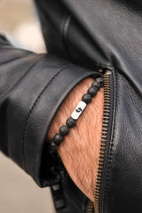 Close up of men's lava stone bracelet on wrist stainless steel engraved