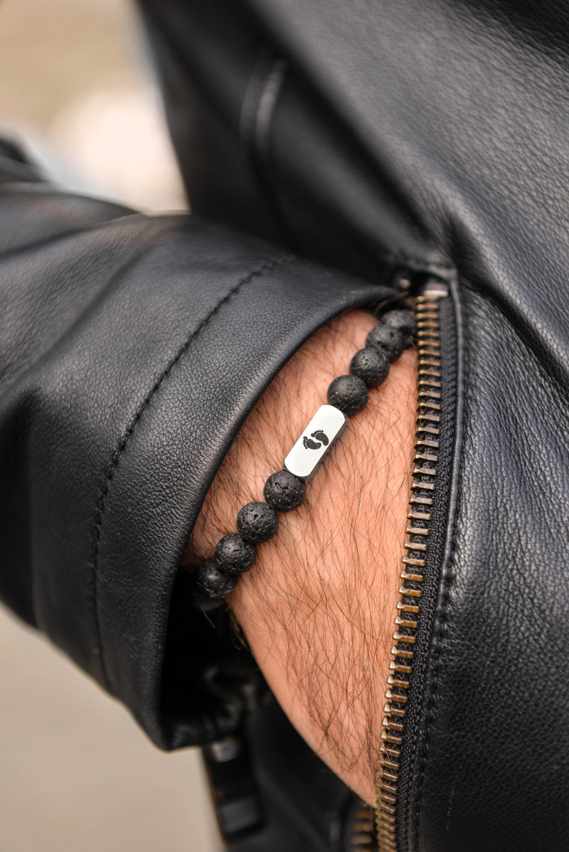 Close up of men's lava stone bracelet on wrist stainless steel engraved