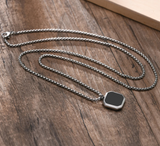 Men's silver stainless steel chain necklace with black onyx square pendant flat lay