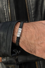 Close up of engraved silver bead on men's woven leather bracelet